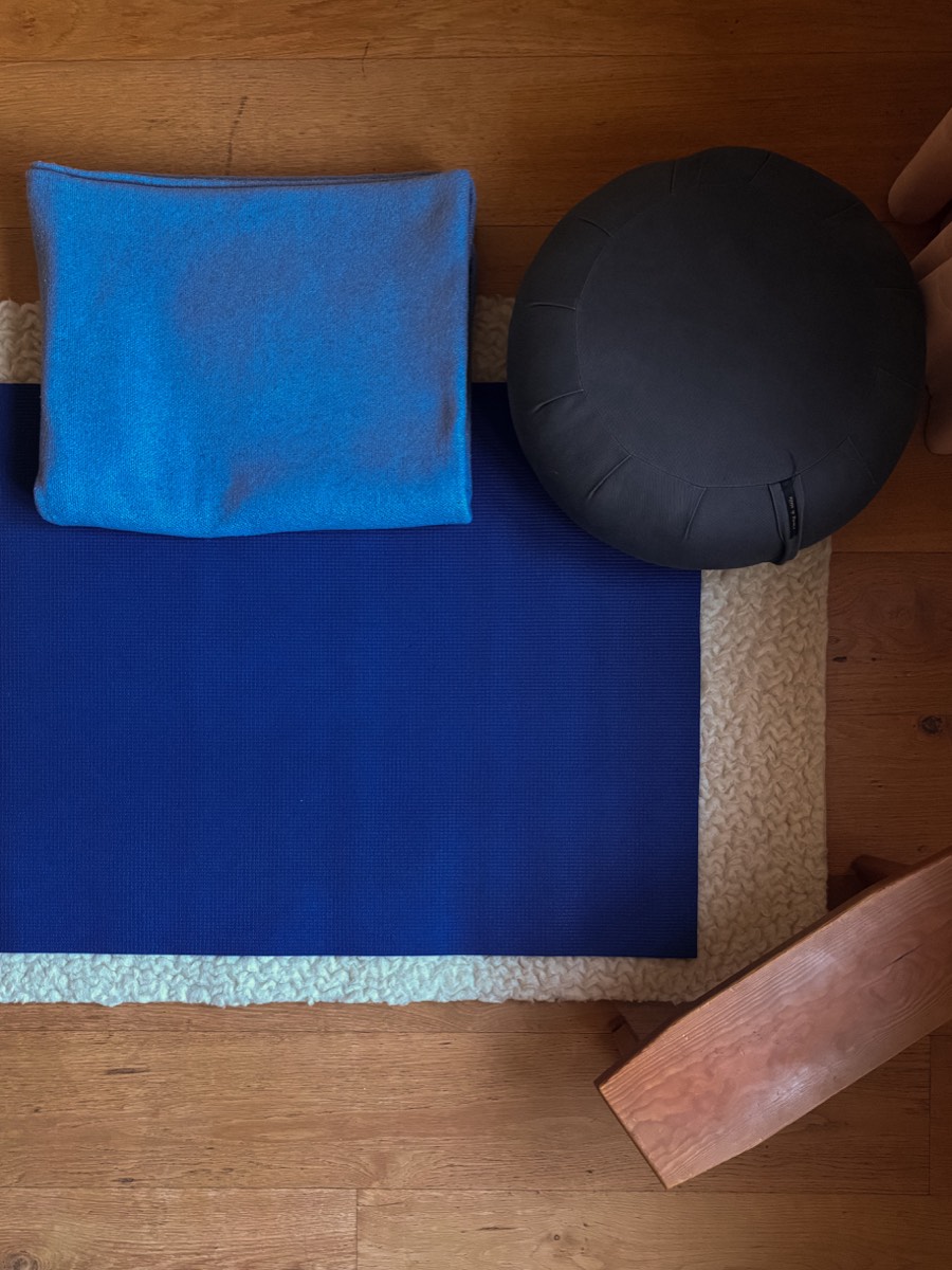 Yogamatte mit Decke und Meditationskissen auf dem Holzboden